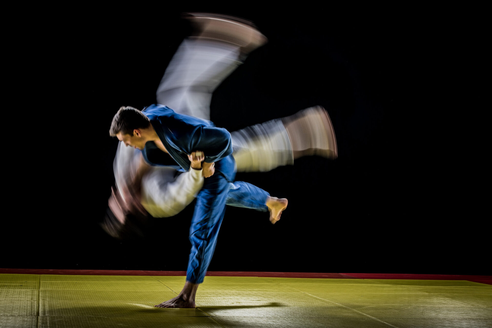 Blurred motion of two male judo players fighting during competition.