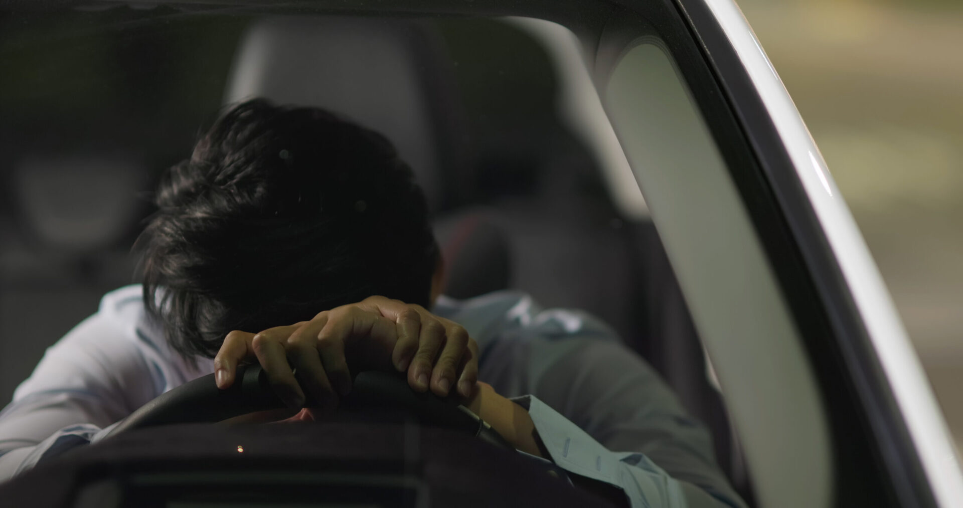 asian businessman feel depressed in car and he is lying on steering wheel at night