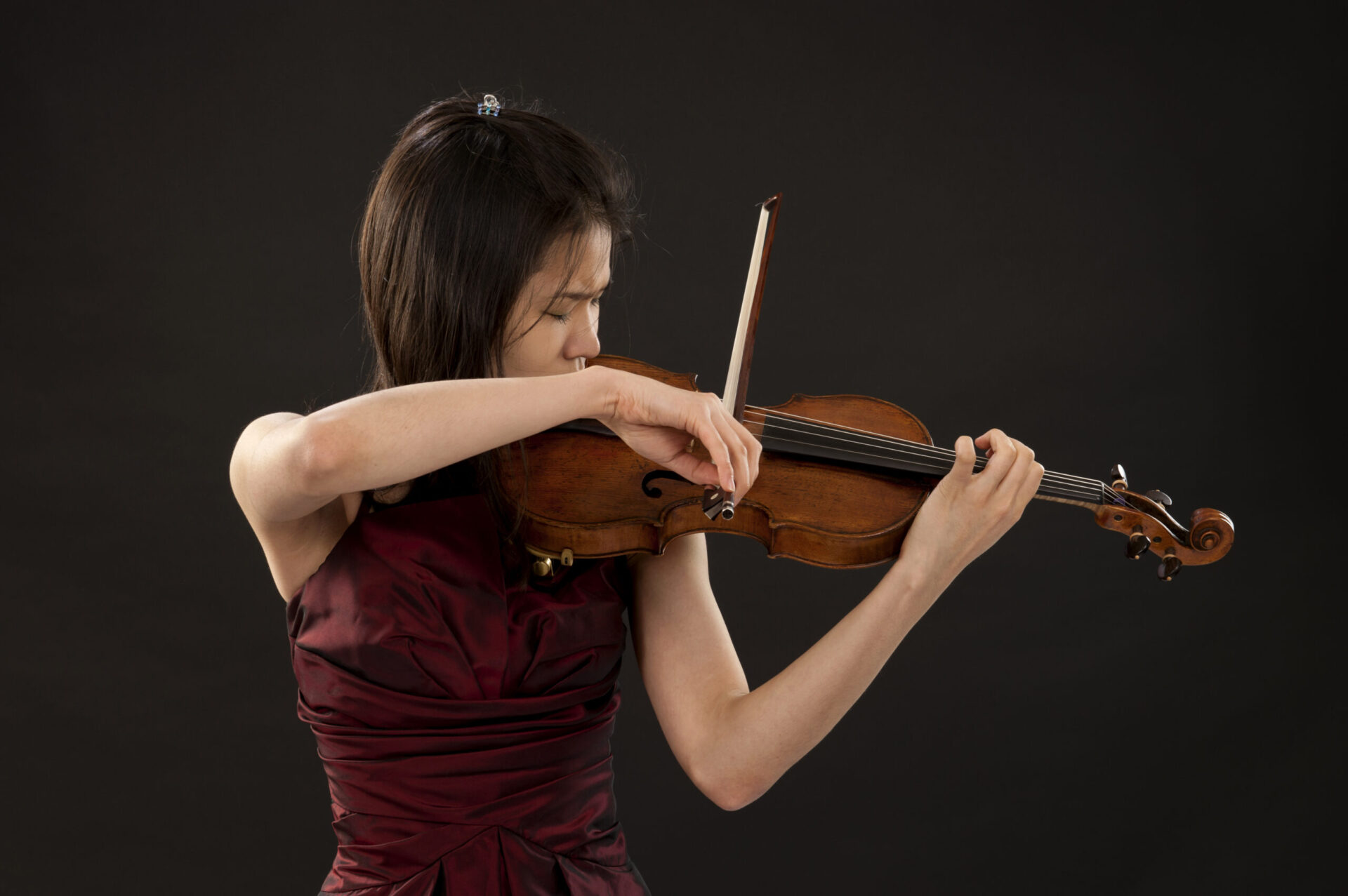 young asian woman playing the violin on black background