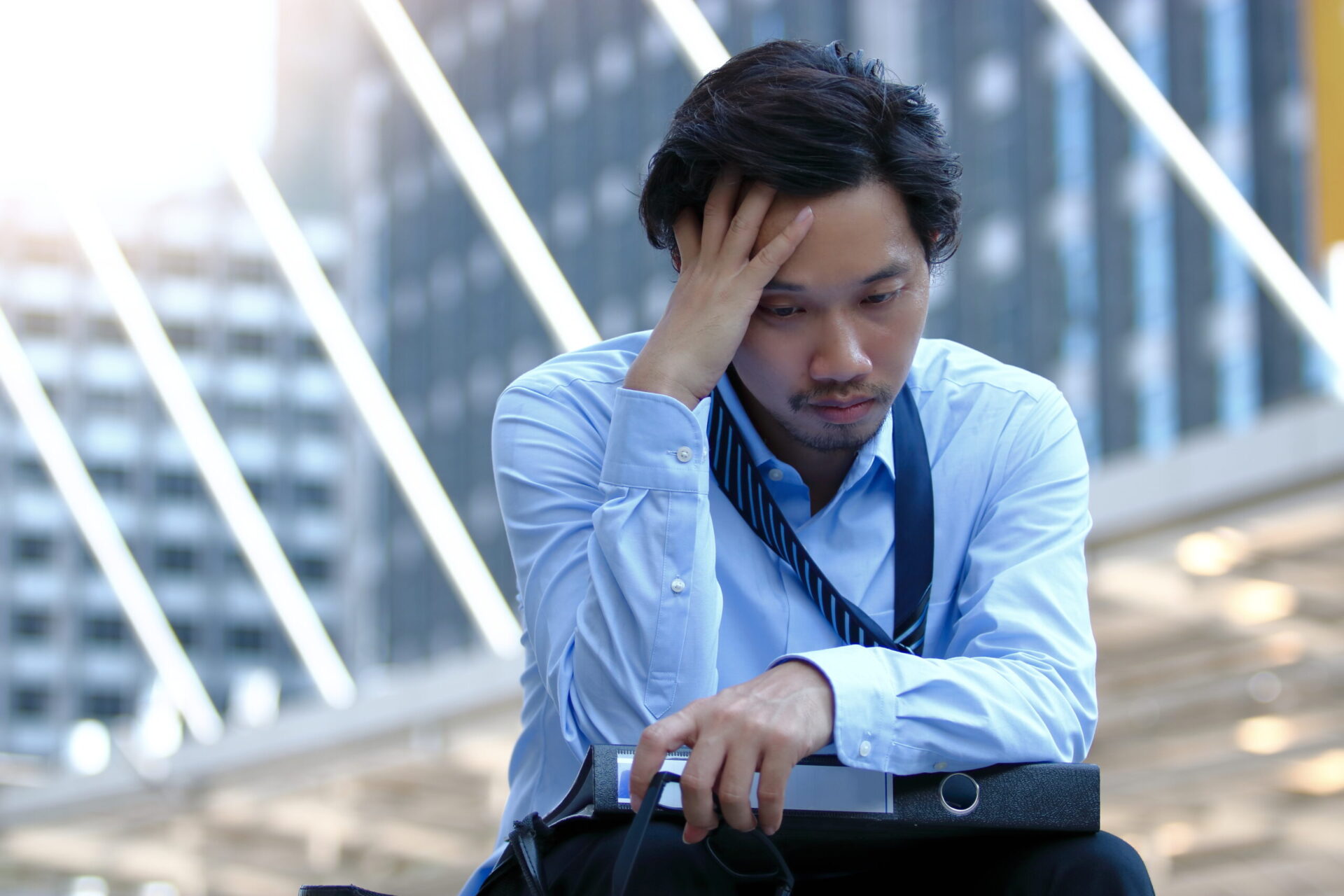 Frustrated stressed young Asian business man touching head and feeling tired or sad his job
