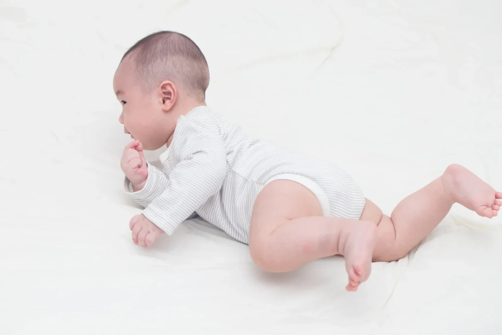 うつ伏せに寝転ぶ赤ちゃんの写真