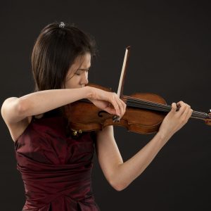 young asian woman playing the violin on black background