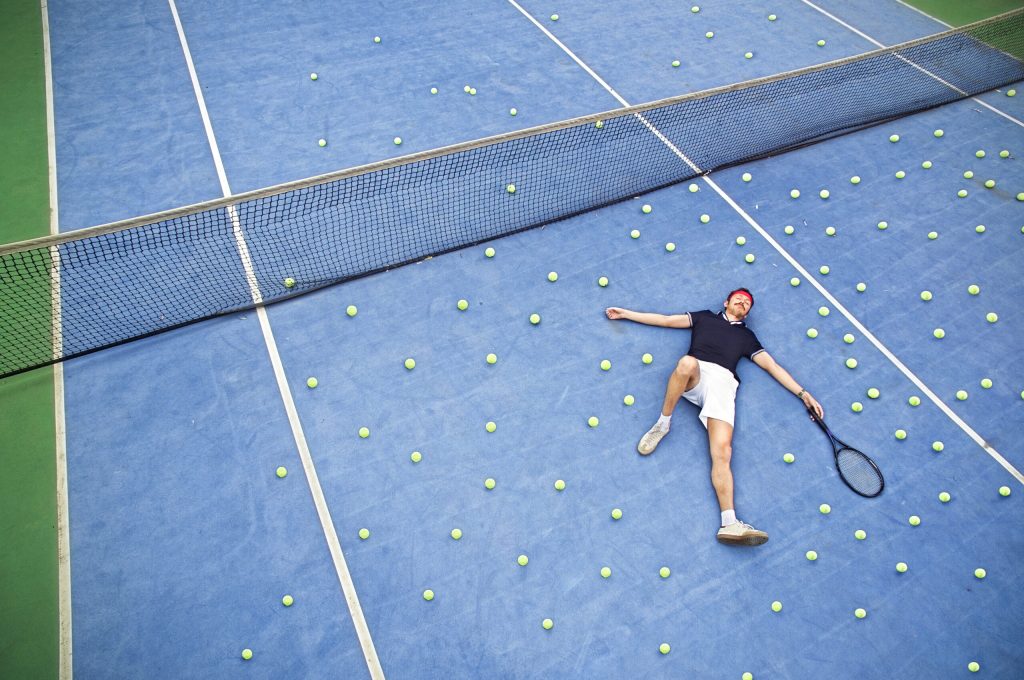 Male tennis player lying on ground