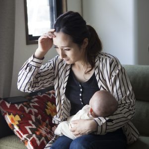 A woman holding a baby does not feel well.